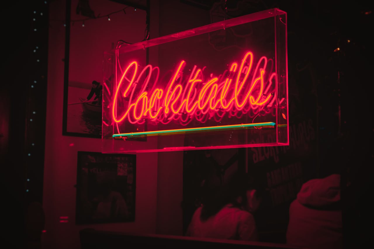 Bright neon 'Cocktails' sign glowing in a lively Dublin bar at night.